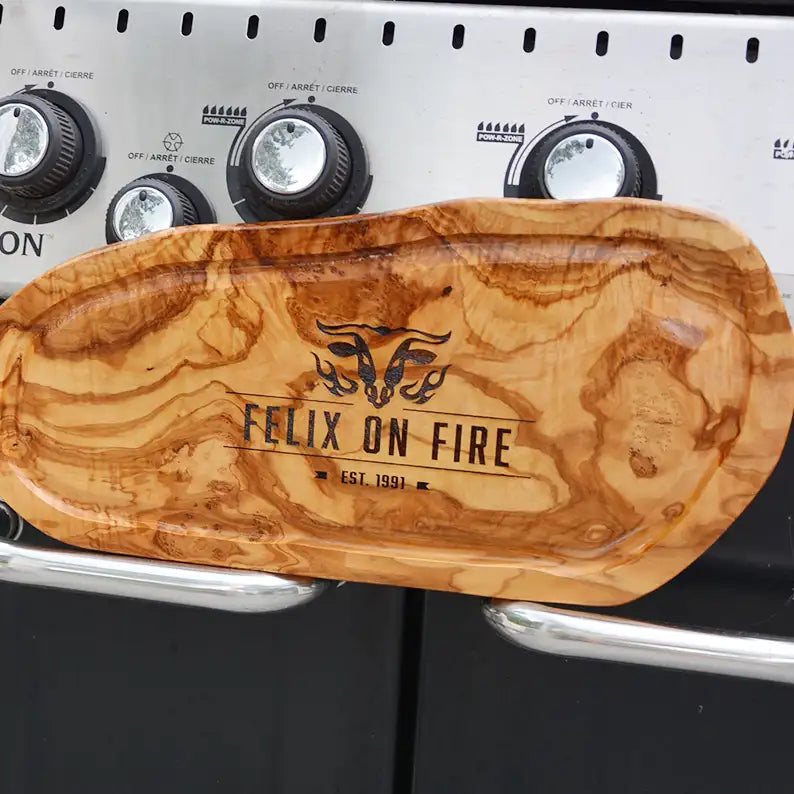 Motiv "On Fire" mit stilisiertem Rinderkopf mit Flammen und Personaliserungsoption mit Name in Großbuchstaben und Datum - Mediterranes Schneidebrett aus Olivenholz mit Saftrille mit und ohne Grifflasche oder Handgriff - Personalisiertes Männergeschenk von Jeske Design