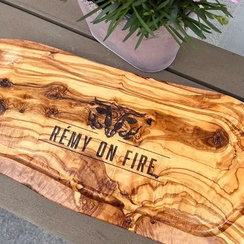 Motiv "On Fire" mit stilisiertem Rinderkopf mit Flammen und Personaliserungsoption mit Name in Großbuchstaben und Datum - Mediterranes Schneidebrett aus Olivenholz mit Saftrille mit und ohne Grifflasche oder Handgriff - Personalisiertes Männergeschenk von Jeske Design