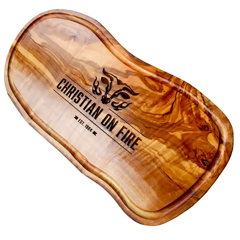 Motiv "On Fire" mit stilisiertem Rinderkopf mit Flammen und Personaliserungsoption mit Name in Großbuchstaben und Datum - Mediterranes Schneidebrett aus Olivenholz mit Saftrille mit und ohne Grifflasche oder Handgriff - Personalisiertes Männergeschenk von Jeske Design