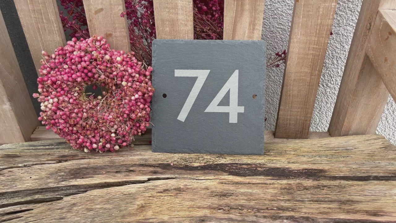 Hausnummer in modernen Ziffern und Buchstaben mit einem Laser auf eine Schieferplatte  in der Größe 15 x 15 cm graviert. Hier Beispiel Nummer 74 mit zwei seitlichen Befestigungslöchern